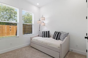 A room with a beige sofa, two windows with blinds, a floor lamp, and a door. - Spacious 4BR Retreat Near East Downtown Houston (Houston)