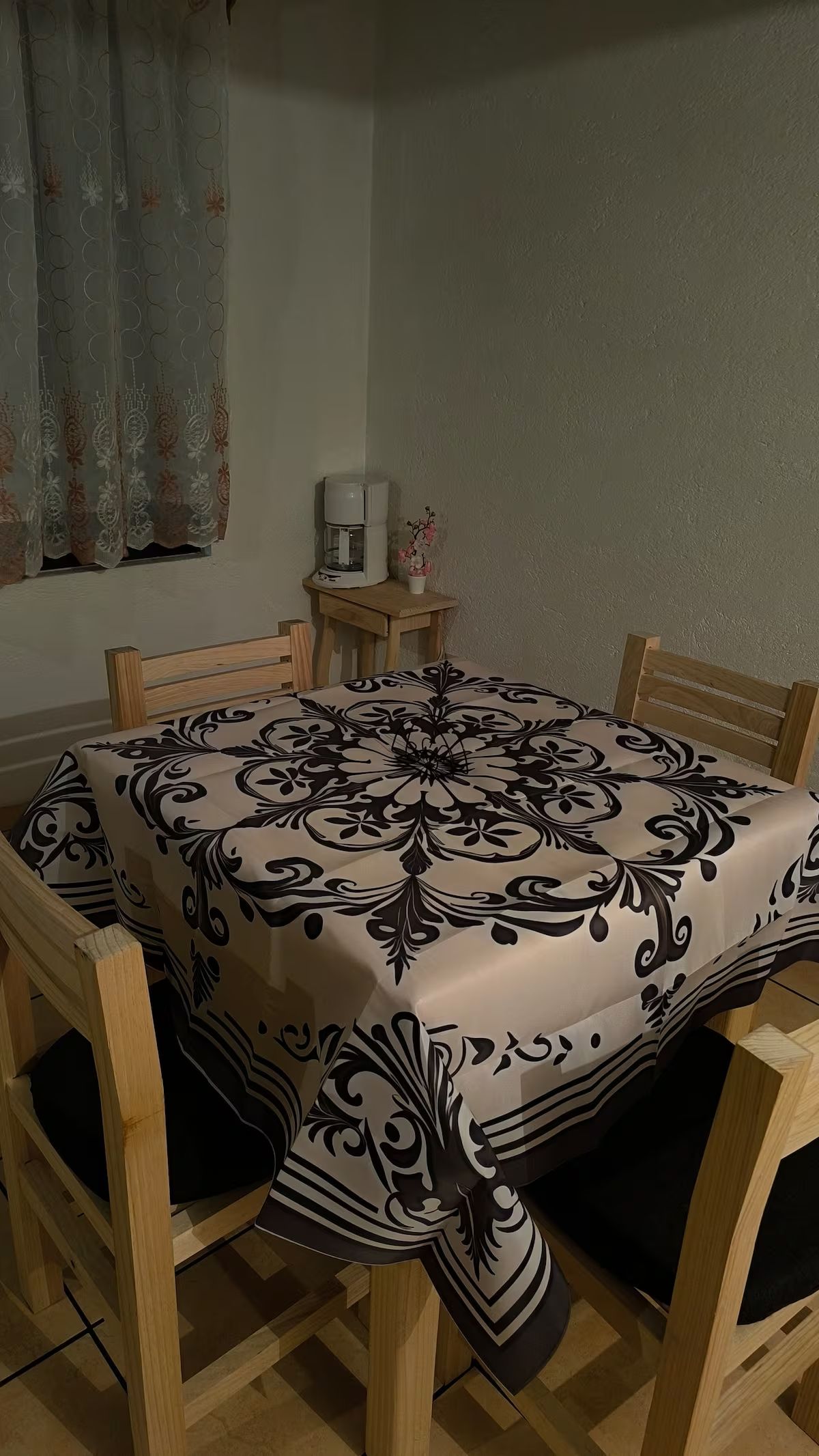 Een eettafel met een tafelkleed met dessin, omringd door houten stoelen.