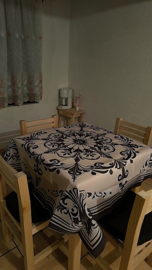 Een eettafel met een tafelkleed met dessin, omringd door houten stoelen.