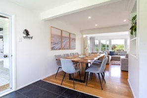 Espaço de refeições com uma mesa comprida, cadeiras cinzas e design moderno.