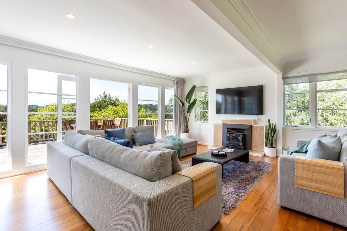 A spacious living room with a large sofa, a coffee table, and a flat-screen TV mounted on the wall.