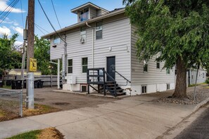 A two-story building with a staircase leading to the entrance, a visible door, and a 'SLOW' pedestrian crossing sign.