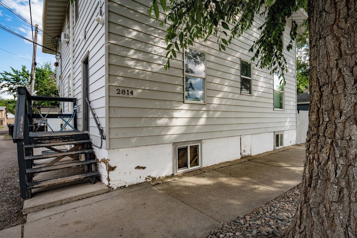 A white house with a number '2814' on the side, a small porch with steps, and a tree in the foreground.