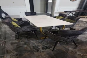 Ett konferensrum med ett marmorgolv, ett vitt bord och stoppade stolar med kuddar.