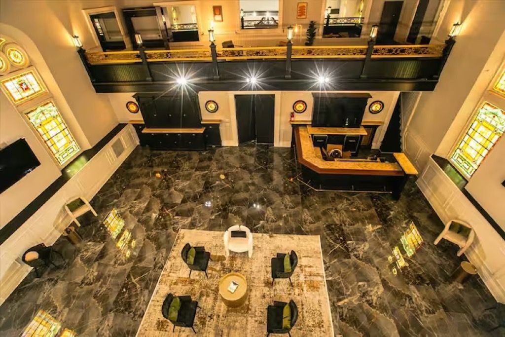 A lobby with a marble floor, a reception desk, and a seating area with chairs and a table.