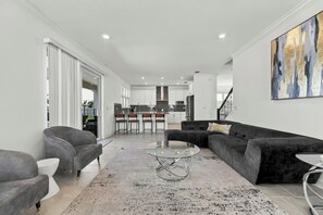 A modern living room with a grey sofa, a glass coffee table, and a black and white rug. - The Luxe Nova - Private Heated Pool/Hot tub and Grill included (Melbourne Beach)