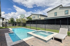 A swimming pool with a surrounding fence, a lounge chair, and a building in the background. - The Luxe Nova - Private Heated Pool/Hot tub and Grill included (Melbourne Beach)