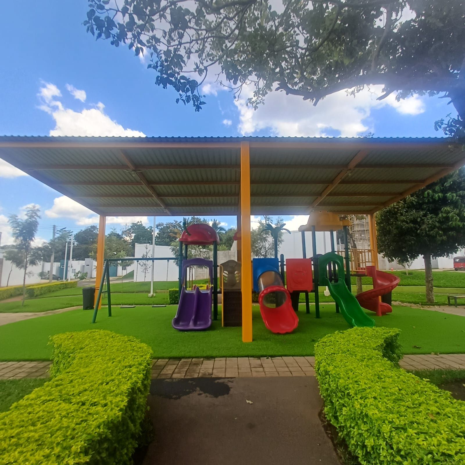 A playground with slides and swings under a covered area.