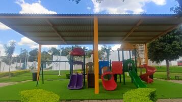 A playground with slides and swings under a covered area.