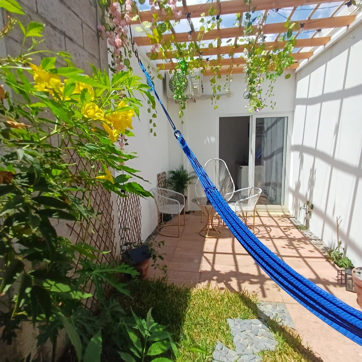 Un patio con una hamaca, sillas y plantas en macetas.
