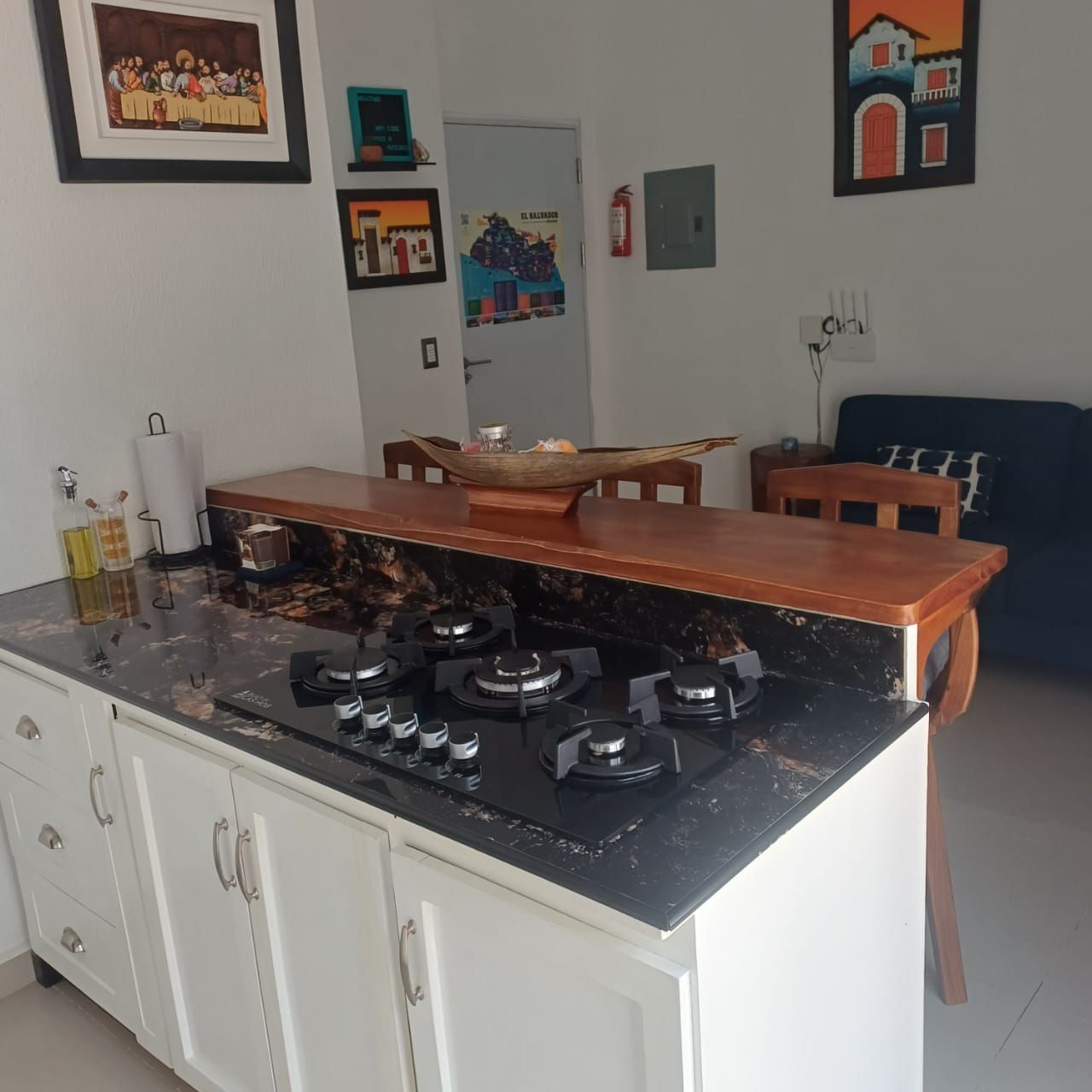 A kitchen with a stove, cabinets, and a dining area with chairs.