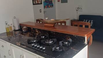 A kitchen with a stove, cabinets, and a dining area with chairs.