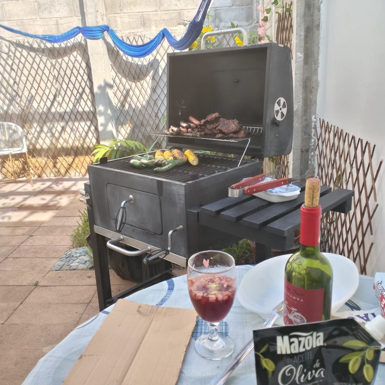 Ein Grill mit Essen, eine Weinflasche und ein Weinglas auf einem Tisch.