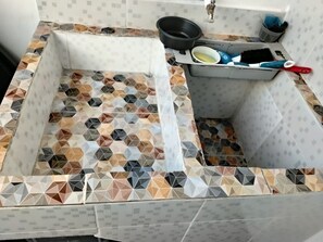 Una cocina con salpicadero de azulejos, un lavamanos y una estufa.