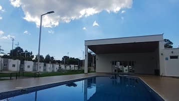 Una piscina con un cielo azul despejado y nubes al fondo.