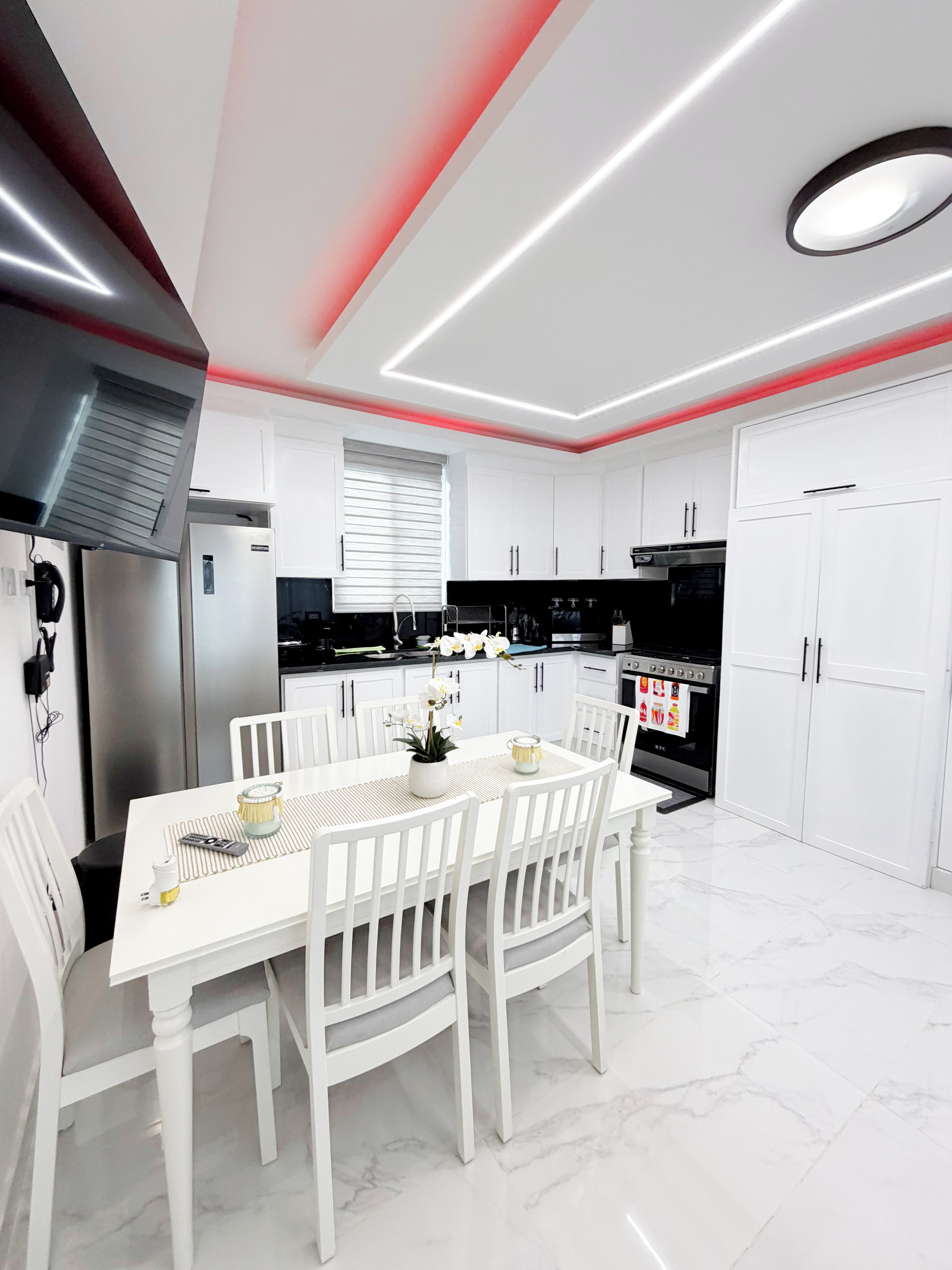 Una cucina moderna con mobili bianchi, un tavolo da pranzo con sedie e un forno a incasso.