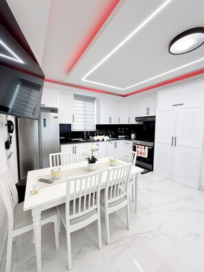 Una cucina moderna con mobili bianchi, un tavolo da pranzo con sedie e un forno a incasso.