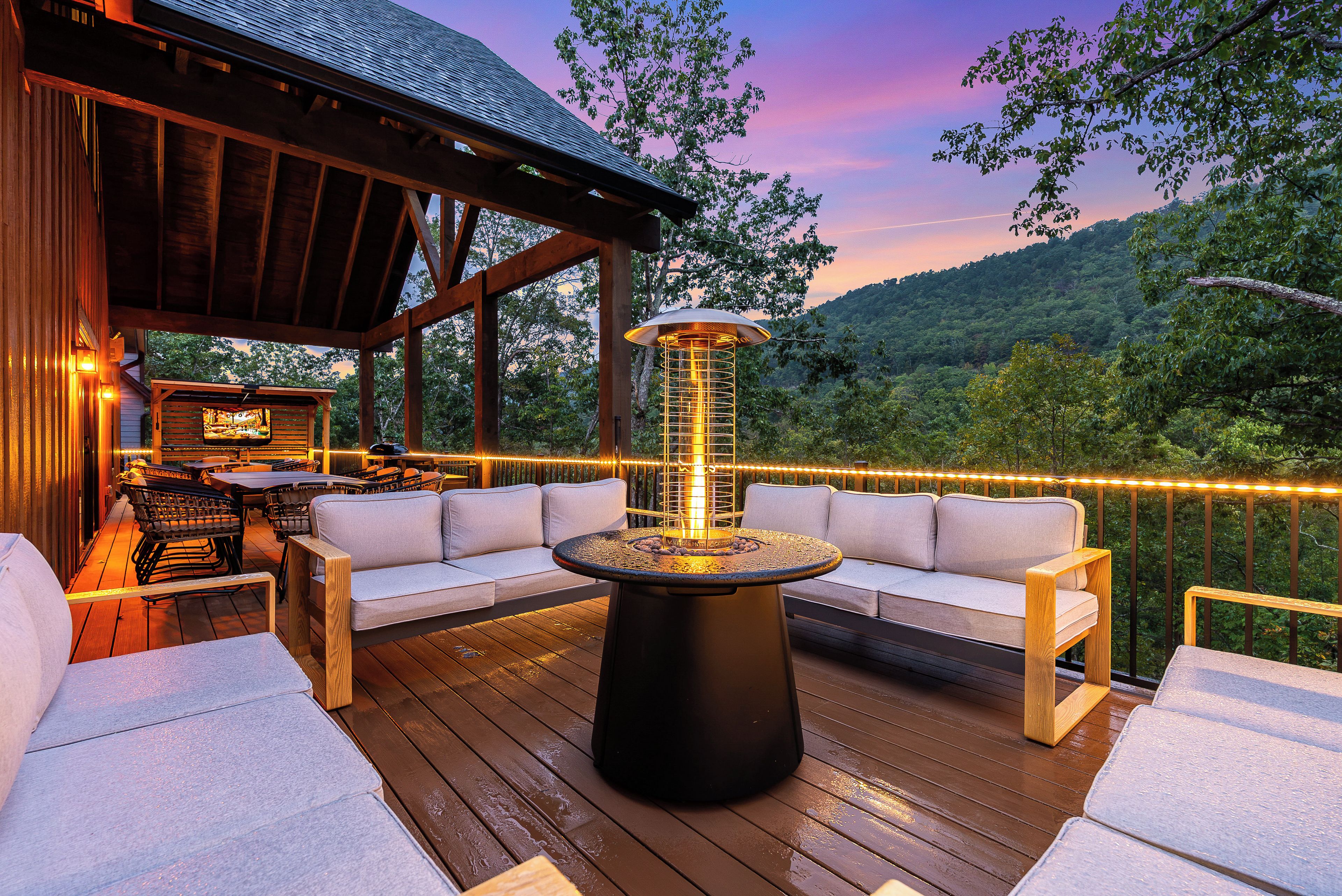 An outdoor deck with a fire feature, seating, and a view of the surrounding landscape.