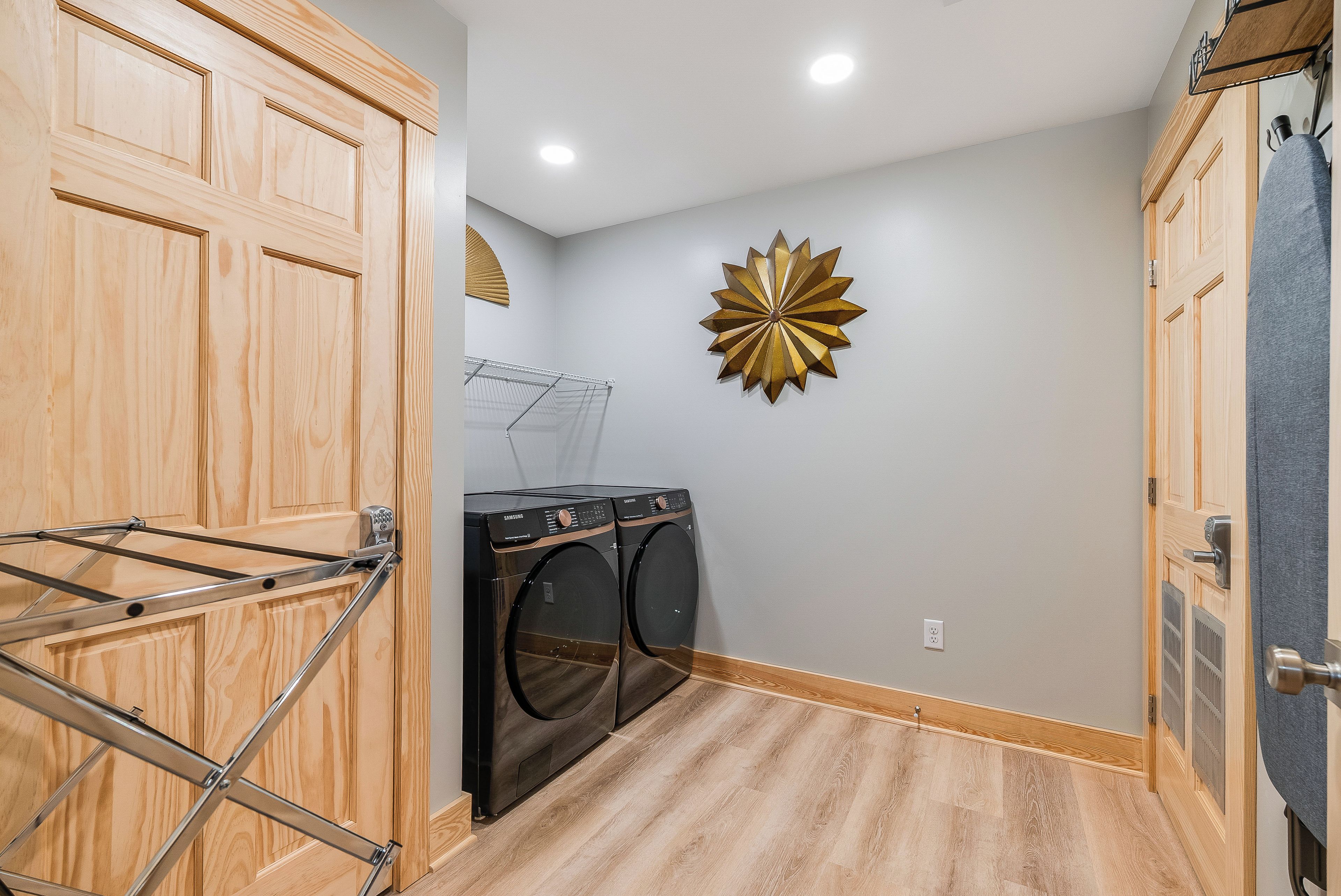 A laundry room with wooden cabinets, a wall-mounted drying rack, and a decorative starburst wall piece.