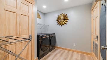 A laundry room with wooden cabinets, a wall-mounted drying rack, and a decorative starburst wall piece.