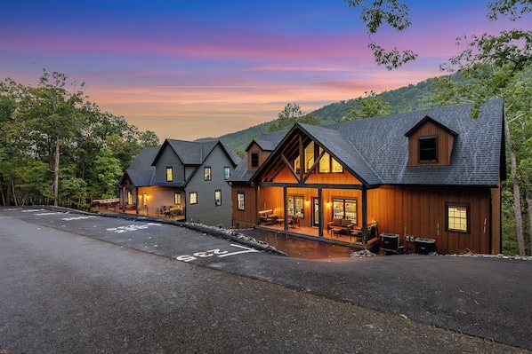 A lodge with a covered outdoor seating area and a view of the surrounding forest.