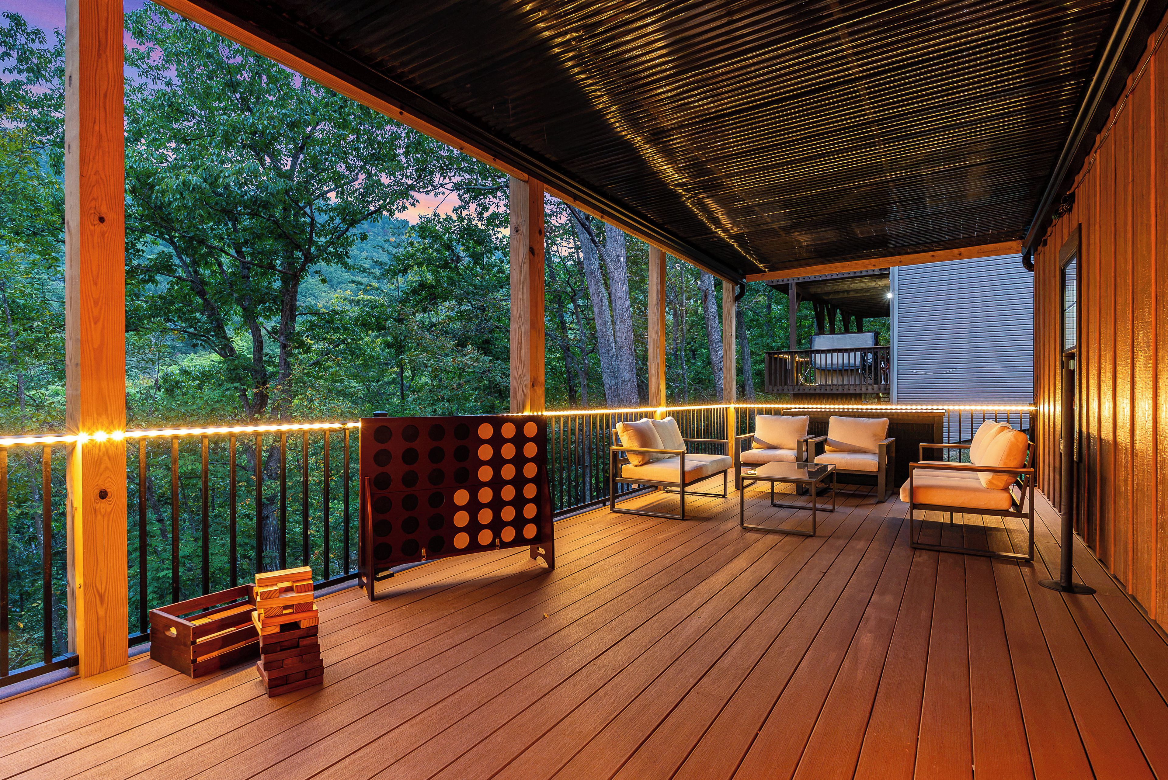 A wooden deck with outdoor furniture, a seating area, and a view of trees.