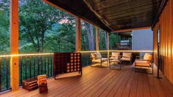 A wooden deck with outdoor furniture, a seating area, and a view of trees.
