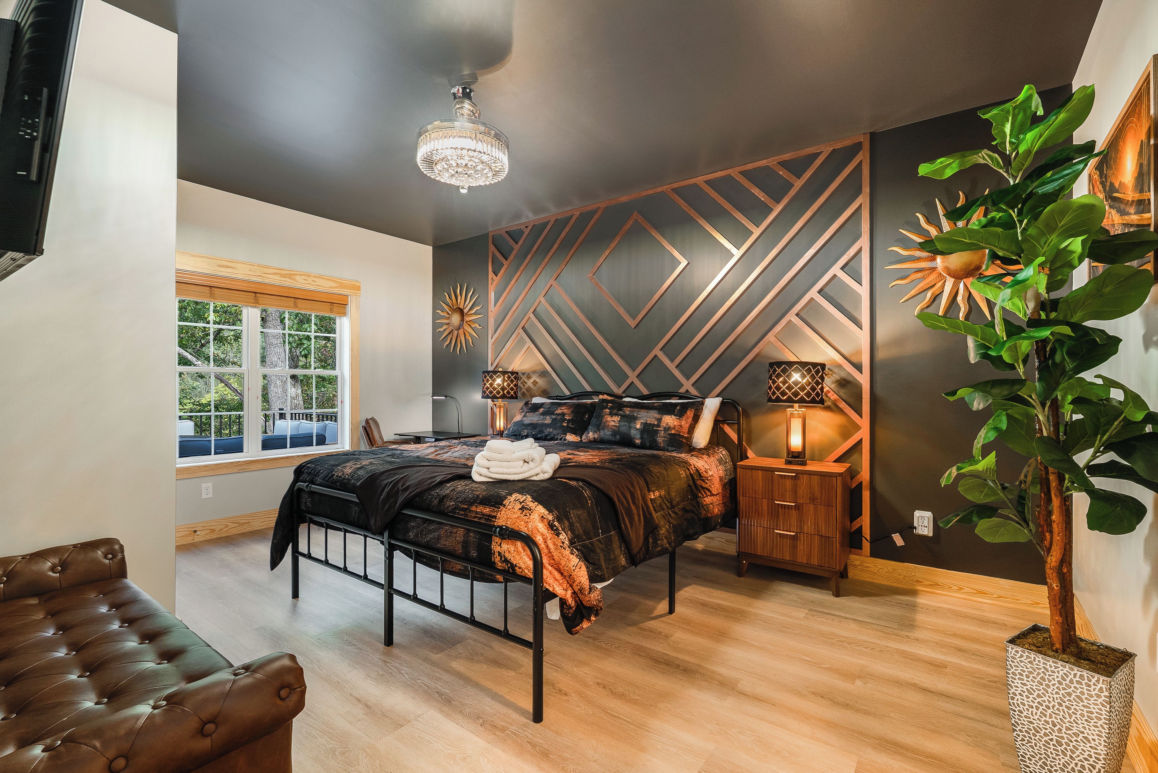 Une chambre moderne avec un lit, des tables de chevet, un lustre et une grande fenêtre.