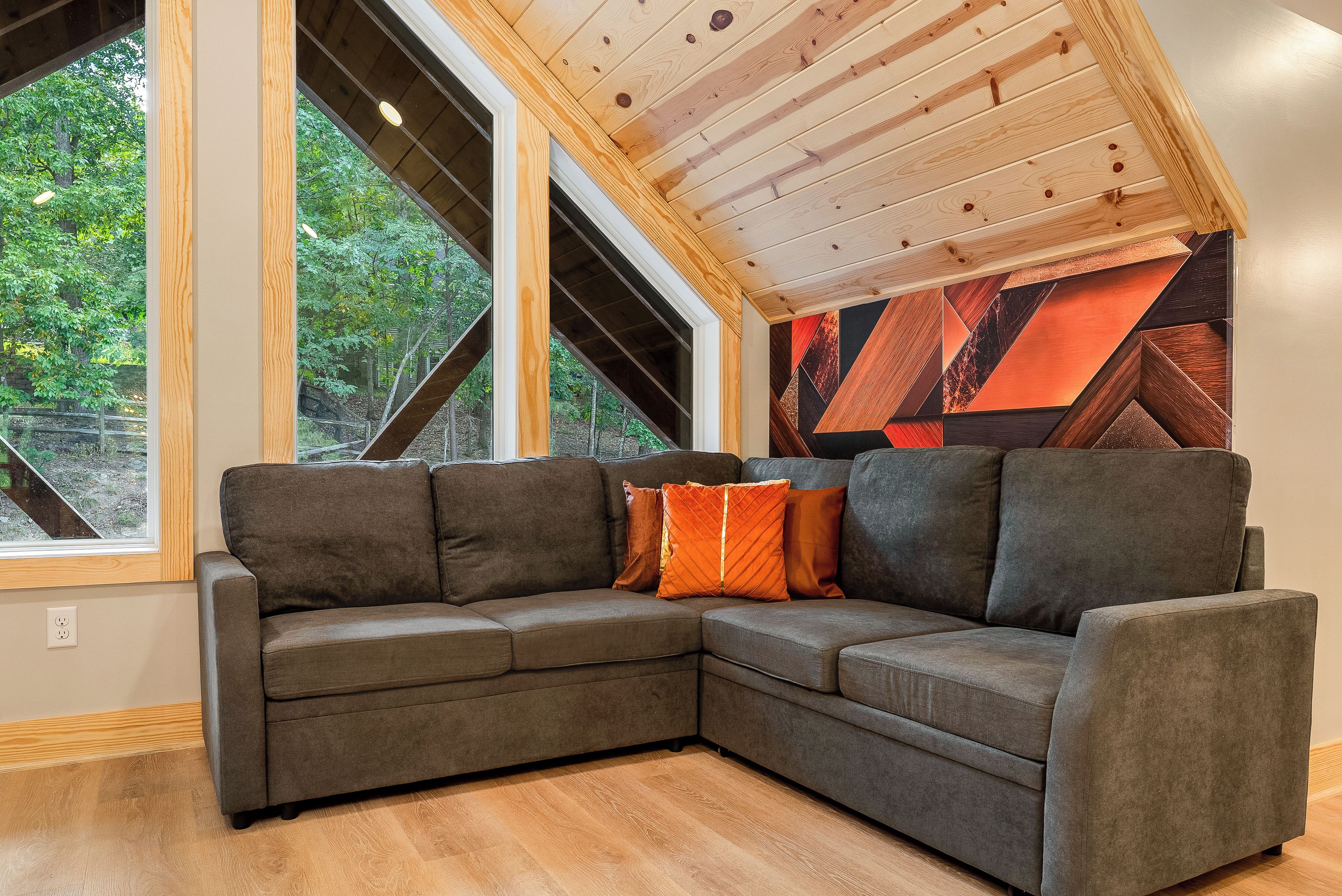 A corner sectional sofa with cushions, a wooden floor, and a sloped ceiling with exposed beams.