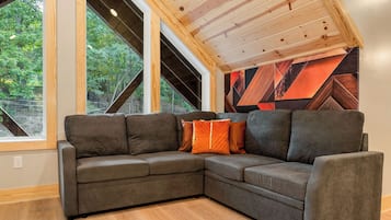 A corner sectional sofa with cushions, a wooden floor, and a sloped ceiling with exposed beams.