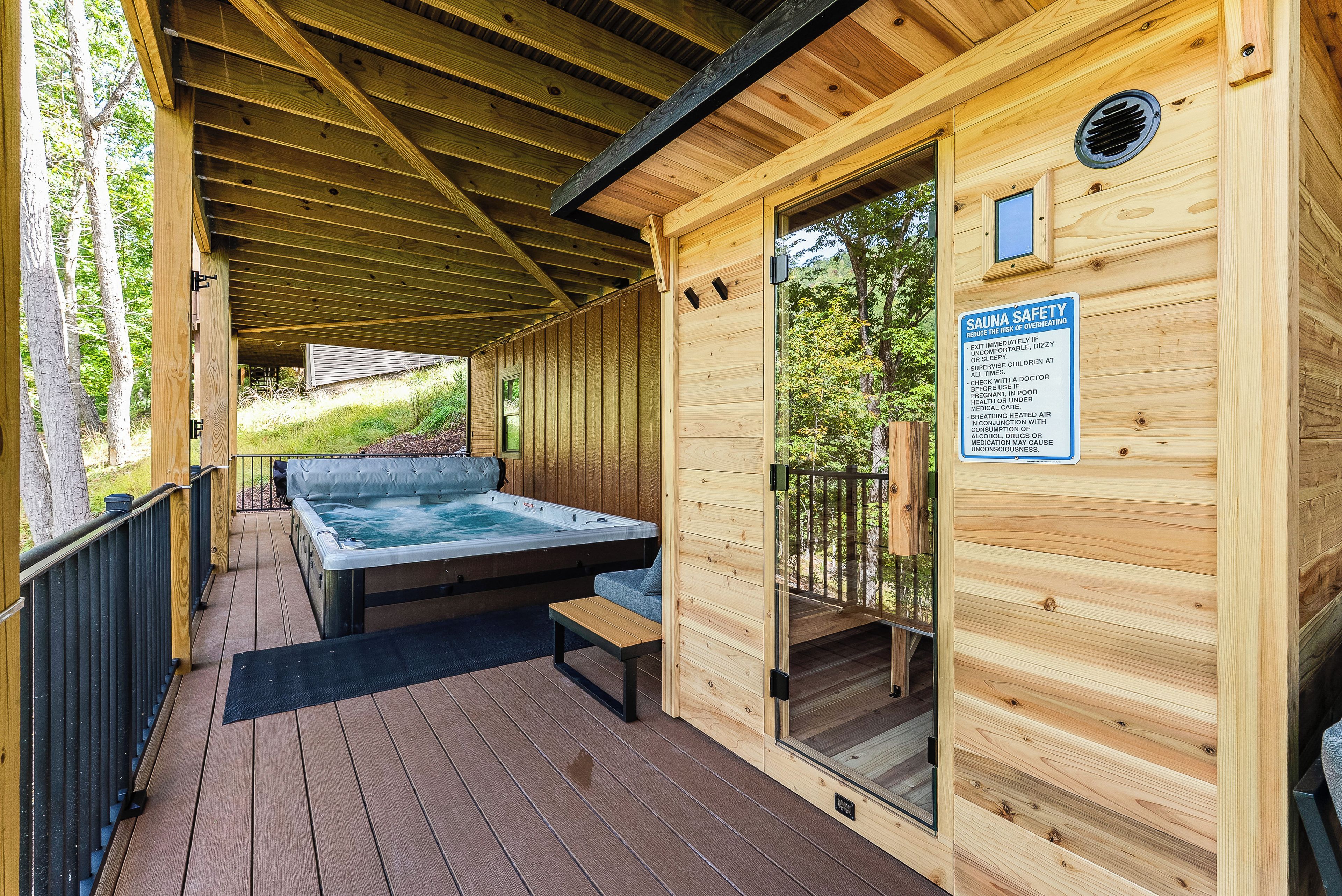 A wooden sauna with a glass door, a hot tub, and a deck area.