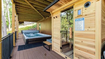 A wooden sauna with a glass door, a hot tub, and a deck area.