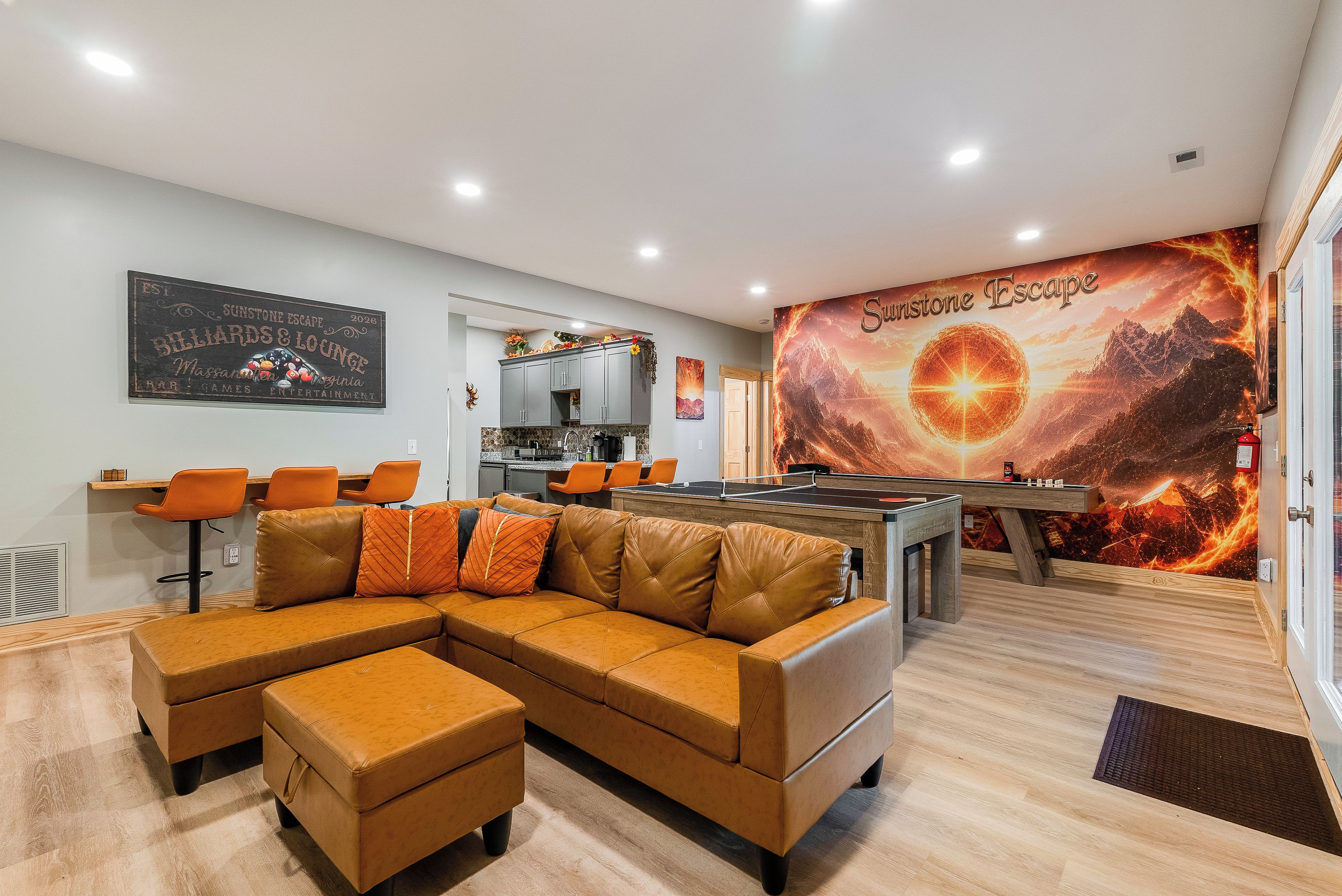 A modern lounge area with a pool table, leather sofa, and a mural depicting a cosmic scene.