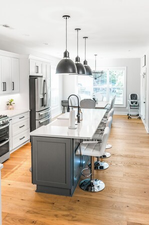 A modern kitchen with a central island, stainless steel appliances, pendant lighting, and a view of the outdoors. - Spacious 5BR Near Liberty University, PS5 & PatioTable Fire Pit, Pack-n-Play (Lynchburg)