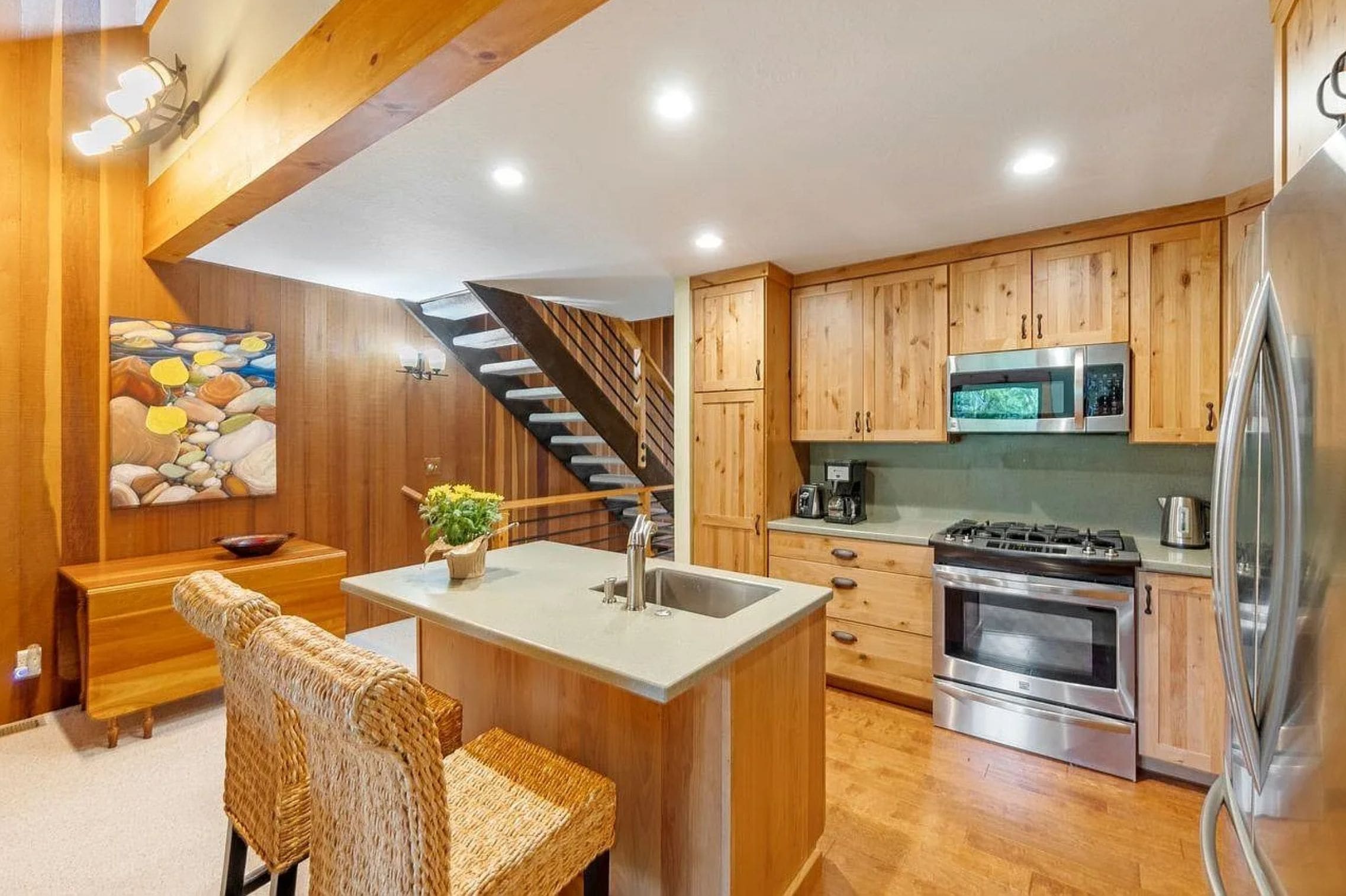A modern kitchen with wooden cabinets, a built-in stove, and a stainless steel refrigerator.