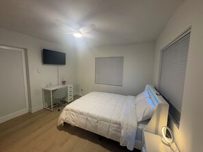 A bedroom with a bed, a desk, a chair, a ceiling fan, a TV mounted on the wall, and a window with blinds. - Welcoming 1-bedroom apartment with AC in vibrant Tampa (Tampa)