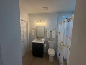 Casa de banho compacta com sanita, lavatório e cortina de chuveiro.