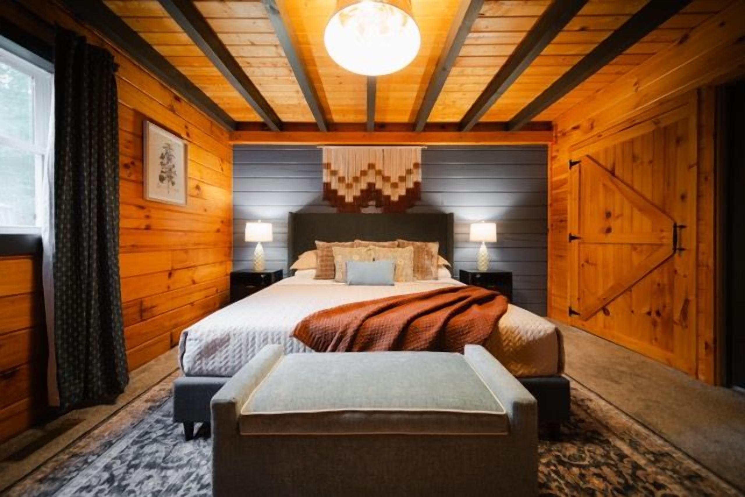 A wooden-paneled bedroom with a bed, bedside lamps, and a bench.
