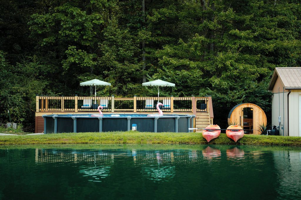 A pool area with a wooden deck, lounge chairs, and a wooden structure with a roof.