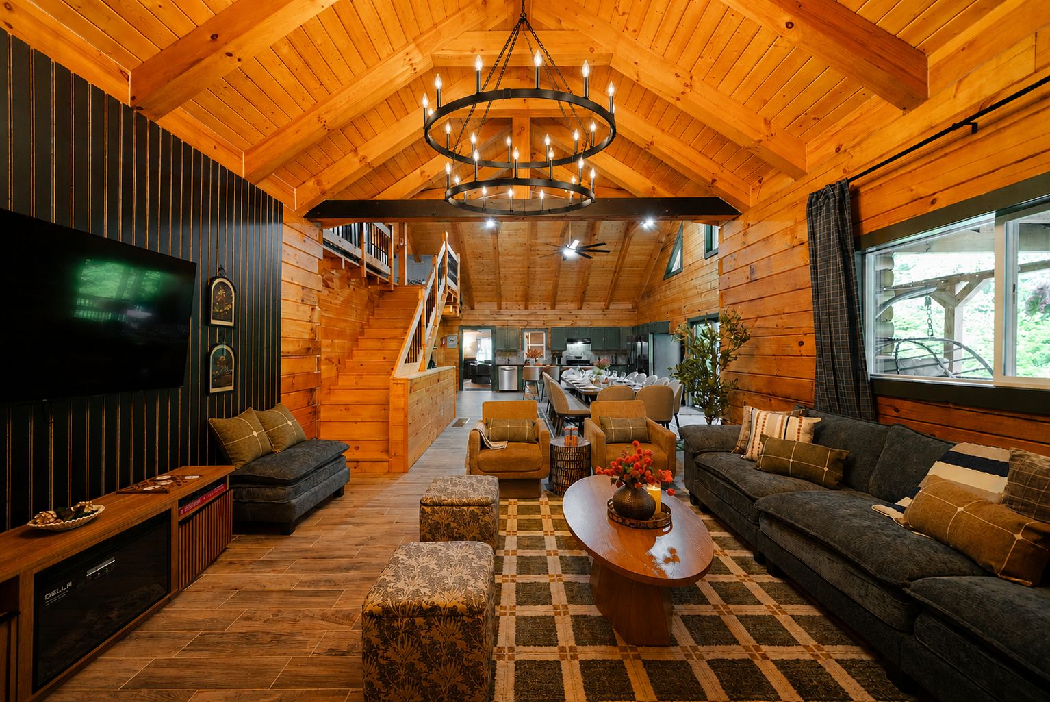 A spacious living room with a wooden ceiling, a large TV, and a cozy seating area with sofas and a coffee table.