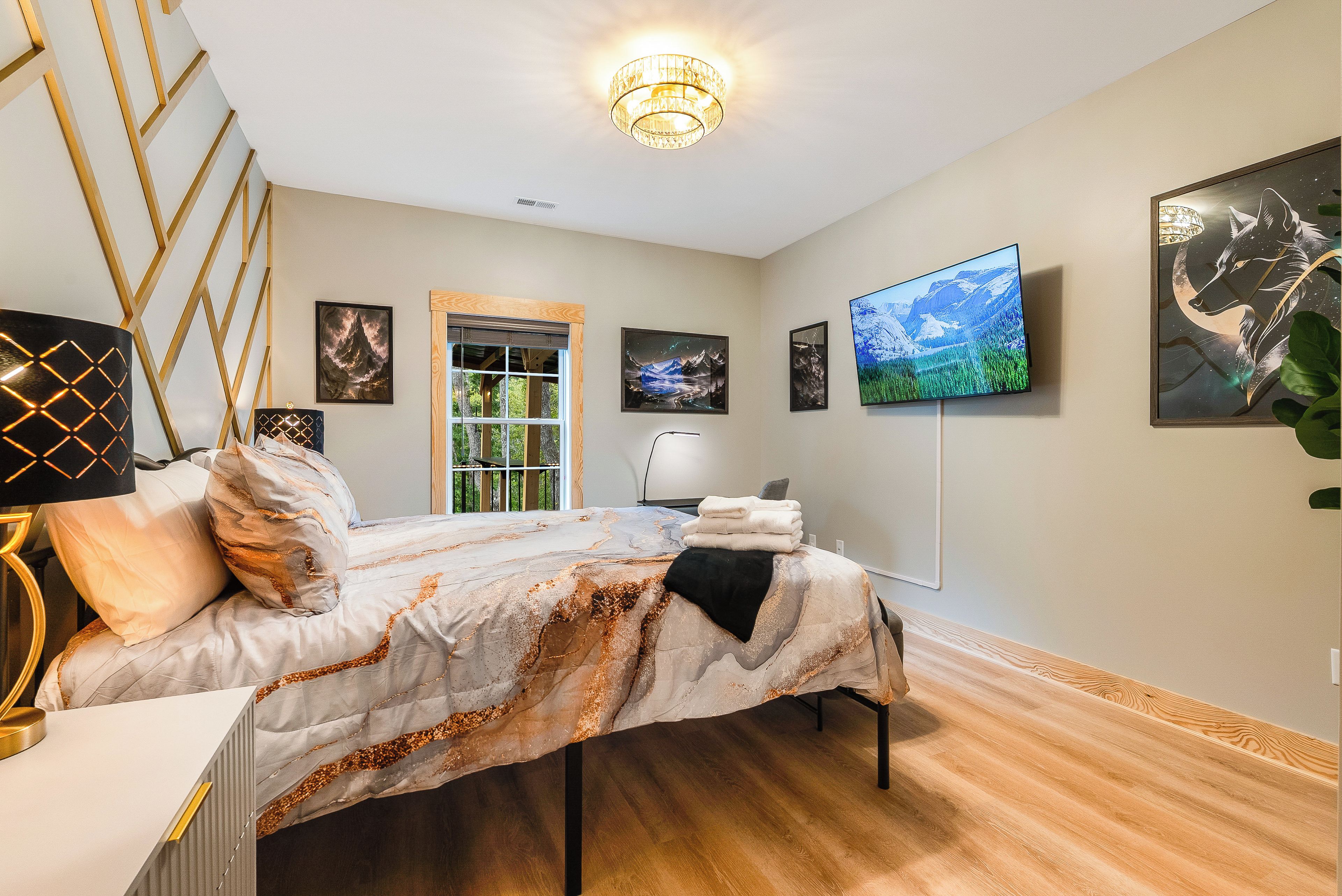 A bedroom with a bed, a television, and artwork on the walls.