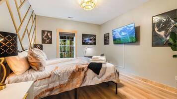 A bedroom with a bed, a television, and artwork on the walls.