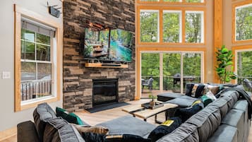 A modern living room with a stone fireplace, large windows, and a comfortable seating area.