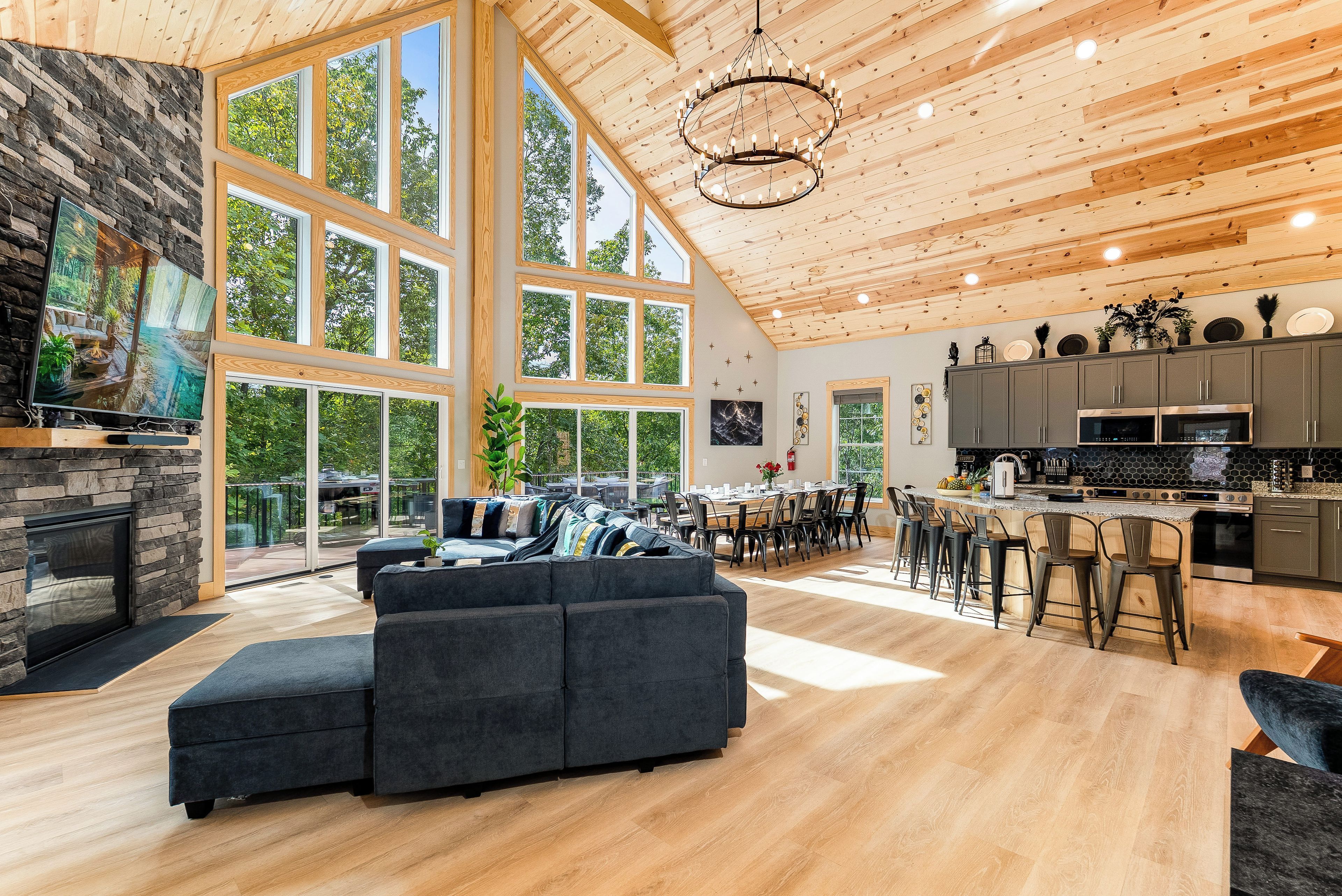 A spacious living area with a large fireplace, a modern kitchen, and a dining area with high ceilings and natural light.