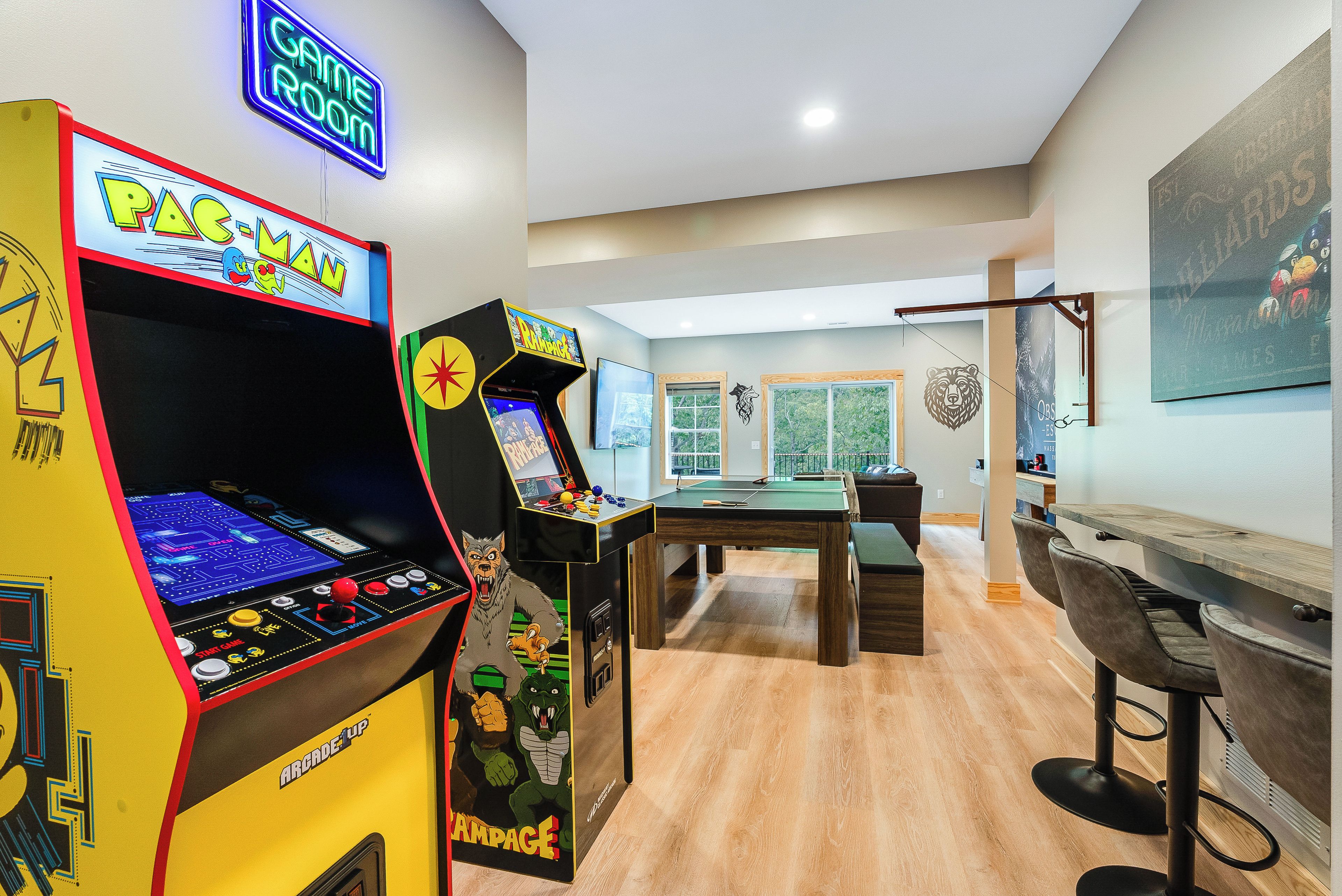 A room with arcade games, a pool table, and a billiards table.