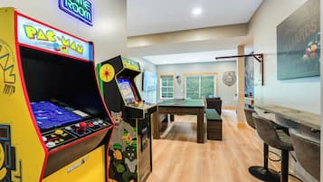 A room with arcade games, a pool table, and a billiards table.