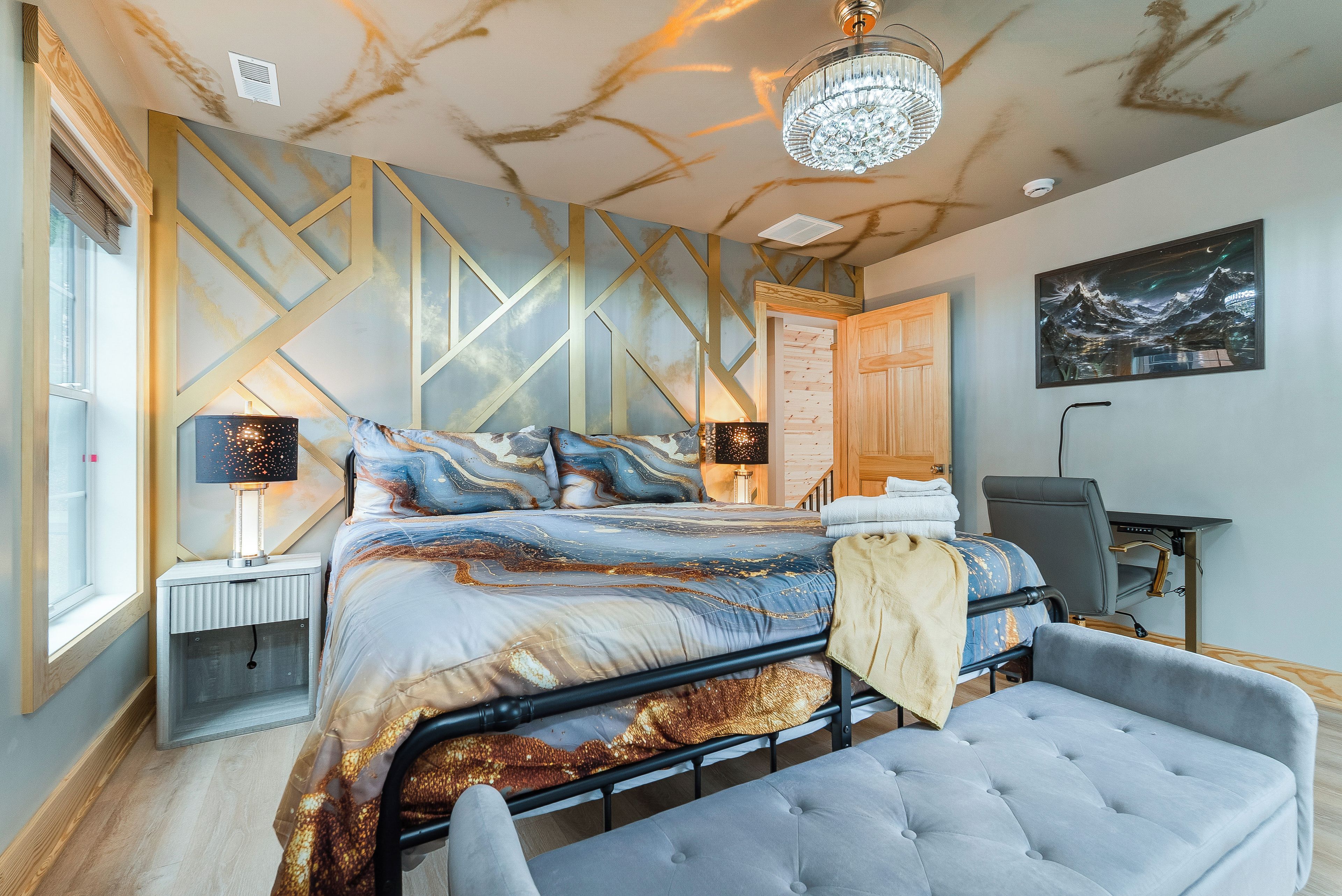 A modern bedroom with a large bed, bedside lamps, a desk, and a chair.