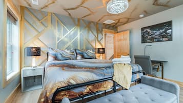 A modern bedroom with a large bed, bedside lamps, a desk, and a chair.