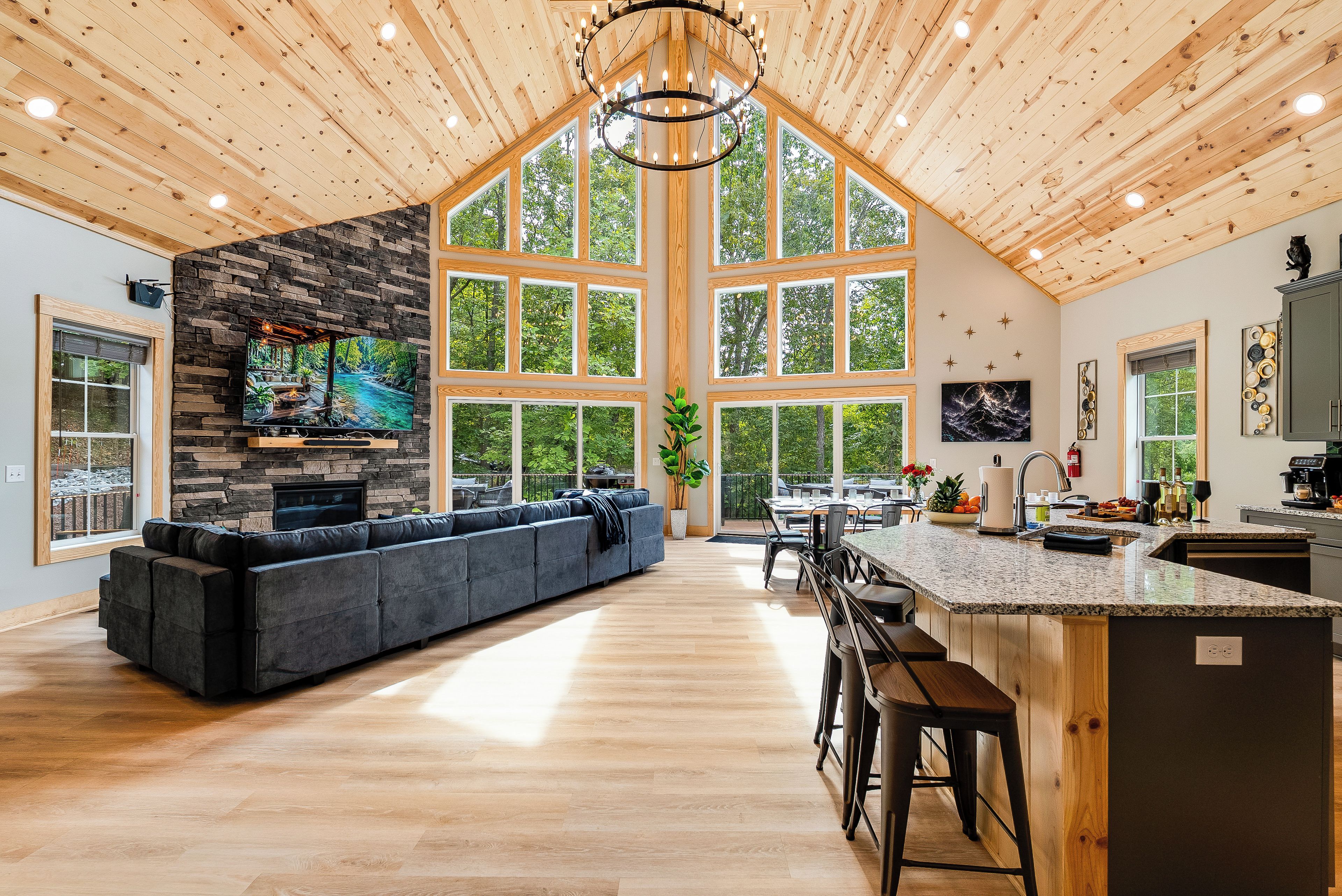 A spacious kitchen with a large island, a stone fireplace, and a dining area with a view of the outdoors.