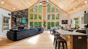 A spacious kitchen with a large island, a stone fireplace, and a dining area with a view of the outdoors.